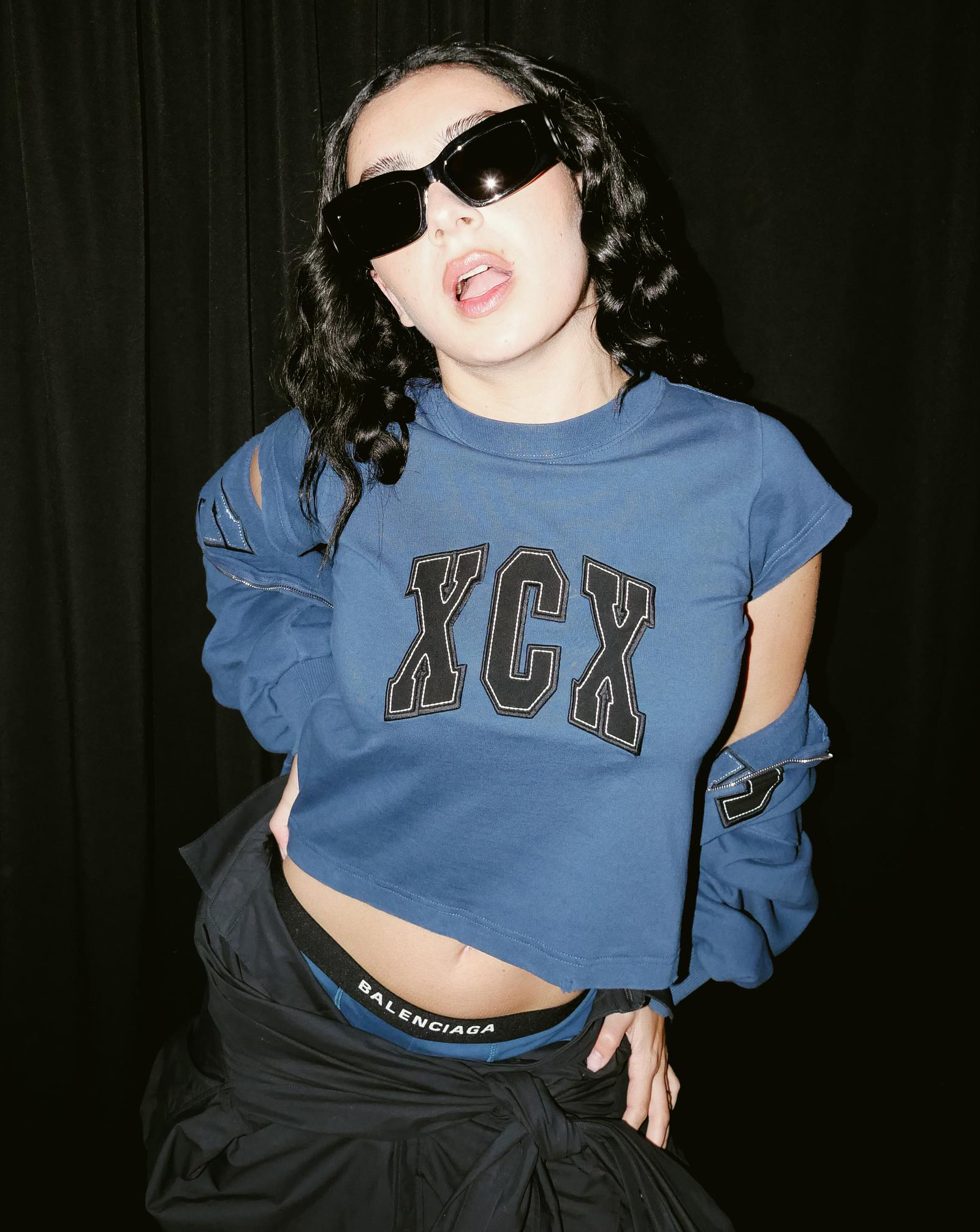 Charli xcx prend la pose dans un pull Balenciaga au logo "XCX".